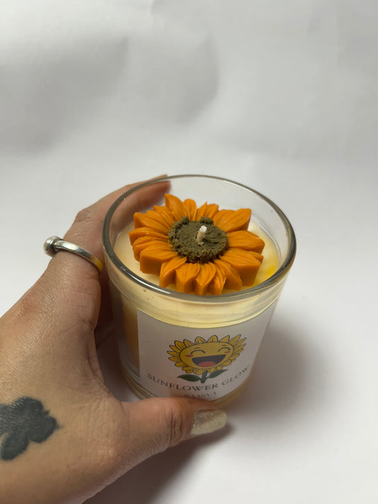 Hand holding a candle with a sunflower design on a white background